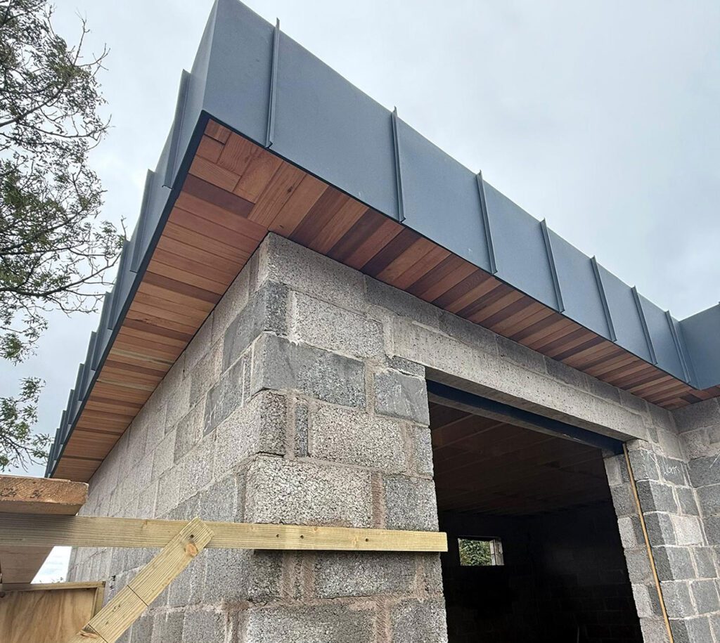 House in Dungannon with a 90m2 Strata waterproofing PVC single ply roof and surrounded Prefa anthracite aluminium standing seam panels